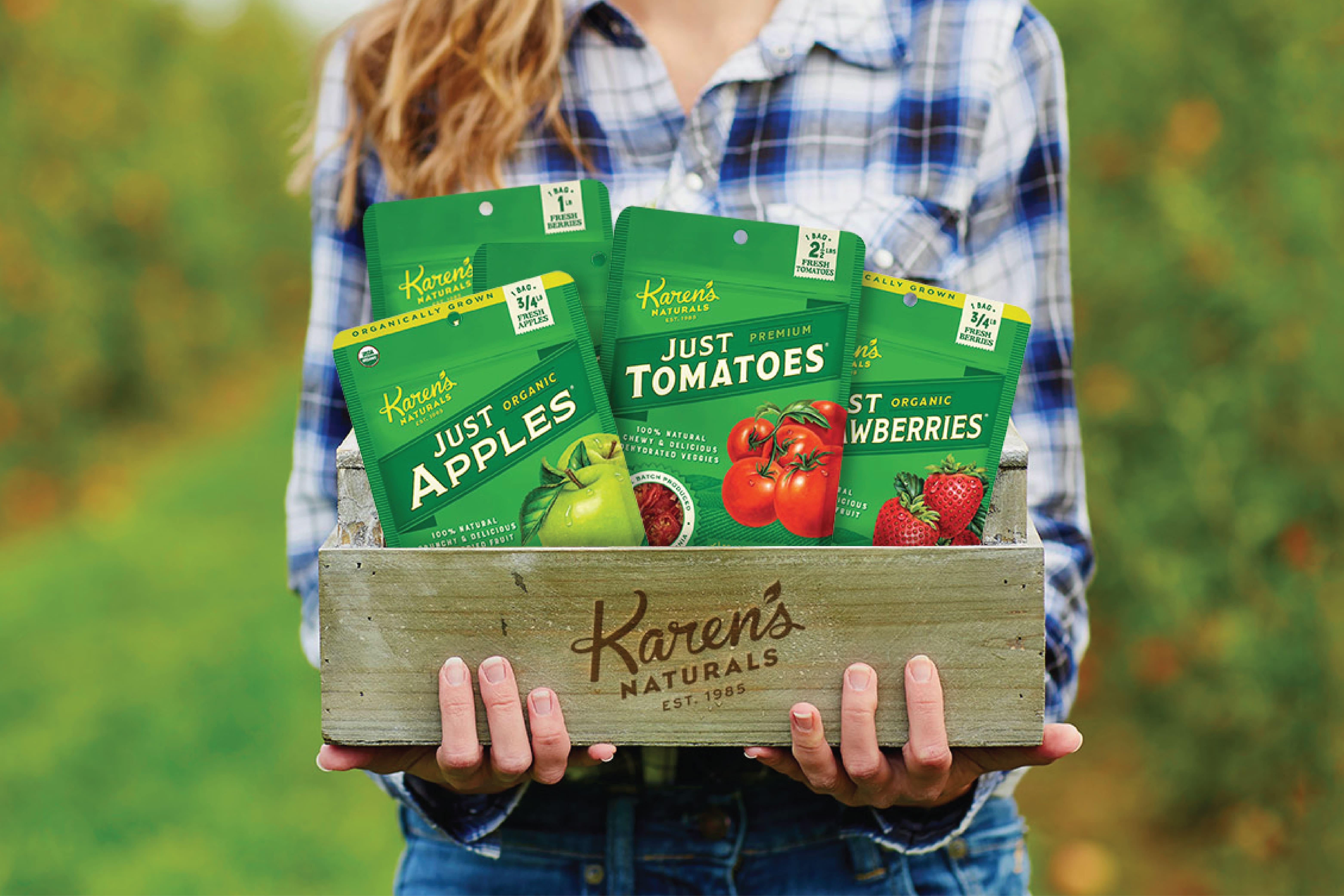 Girl outside holding a wooden fruit crate of filled with Karen's Naturals fresh dried fruit and veggies.
